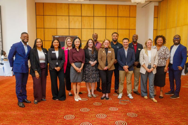 Fifteen colleagues and partners standing together at a conference venue
